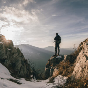 Young man standing on top of the mountain alone and admiring the view